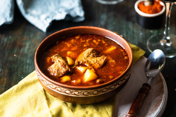 goulash ou guisado em panela de cobre com colher na mesa rústica da cozinha. eintopf, chili con carne. prato húngaro tradicional. jantar caseiro. sopa de páprica. vida morta de comida. ensopado de carne. - soup photography pan hungary - fotografias e filmes do acervo