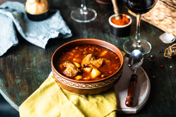 goulash ou guisado em panela de cobre com colher na mesa rústica da cozinha. eintopf, chili con carne. prato húngaro tradicional. jantar caseiro. sopa de páprica. vida morta de comida. ensopado de carne. - soup photography pan hungary - fotografias e filmes do acervo