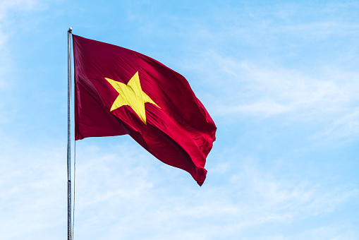 Vietnam flag flies in the wind against a blue sky