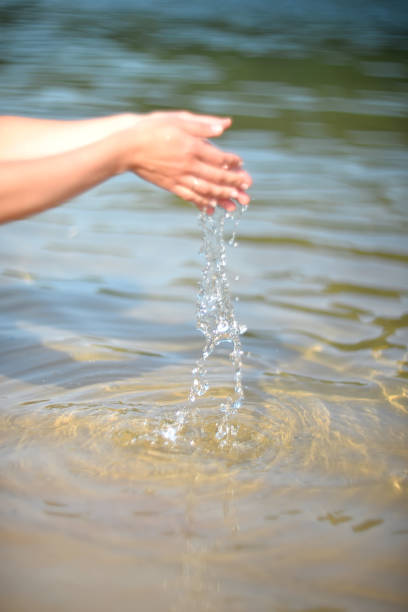 istock water pours from the hand into the water. summer background 1227085718