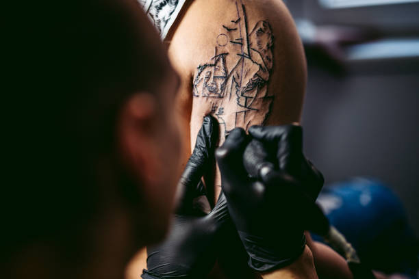Tattoo artist tattooing a man's arm in his tattoo studio.