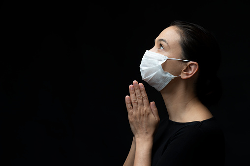 Masked woman is praying for Coronavirus.