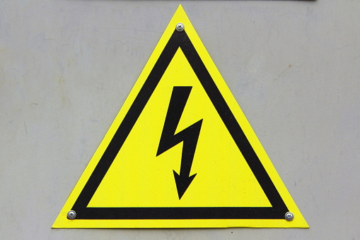 Sign of danger of electric shock on white isolation background. Black lightning against a yellow triangle. Stock photo with empty space for text and design.