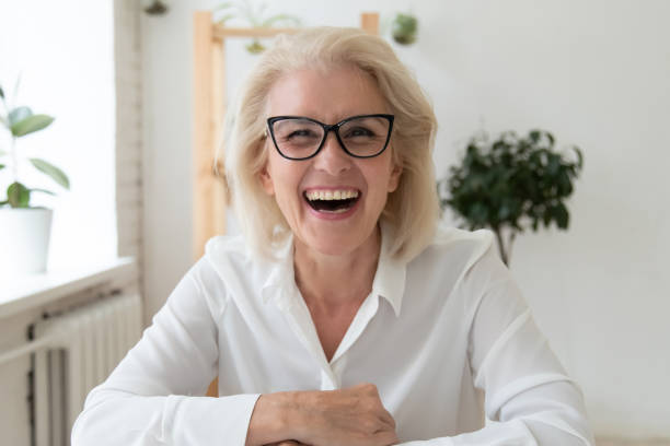 Headshot of smiling middle-aged woman speak on video call Headshot portrait of excited mature businesswoman in glasses have fun laugh talking on video call, overjoyed happy middle-aged woman employee smile joke speaking online on WebCam conference webcam photos stock pictures, royalty-free photos & images