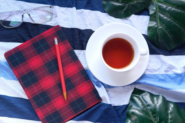 Top view of tea, notebooks and a pen on table cloth