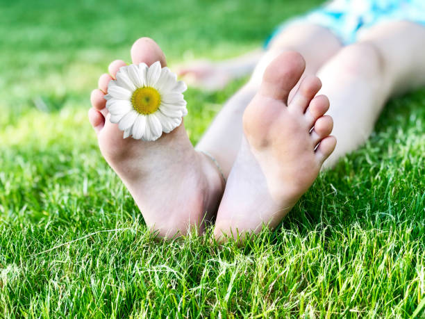 istock Barefoot kid lying on green grass against blurred background. Having fun outdoors in spring park 1227089394