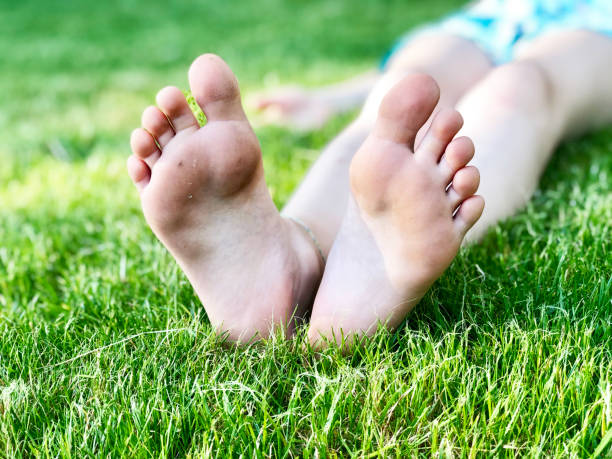 istock Barefoot kid lying on green grass against blurred background. Having fun outdoors in spring park 1227089397