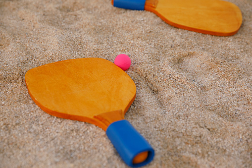 Beach tennis rackets and ball  At the sandy beach  Beach holiday Set for a game close-up wooden rackets