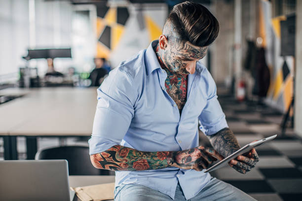 istock Modern businessman with whole body covered in tattoos using digital tablet in office 1227094040
