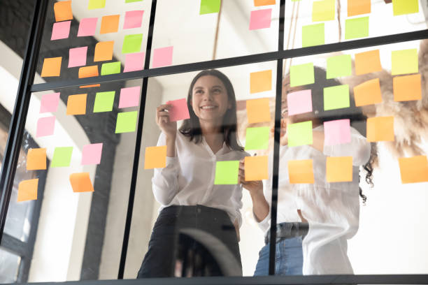 istock Two smiling diverse businesswomen planning project on sticky papers 1227094271