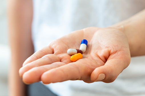 Close-up of woman hands holding medicine pills