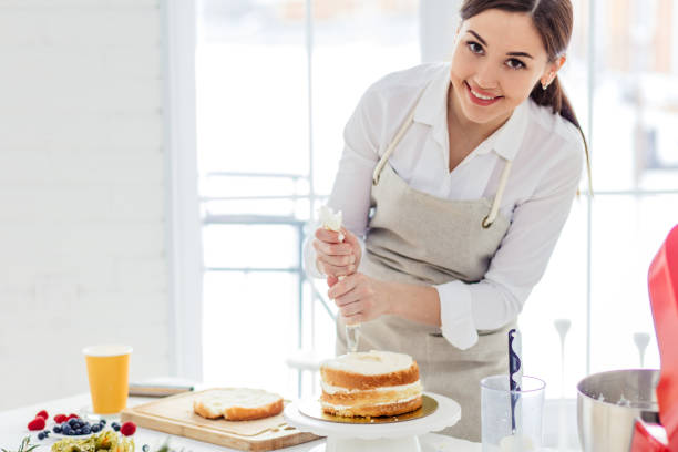 istock pretty girl adding butter mixture on the cake 1227094889