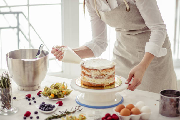 キッチンでケーキにクリームを絞る素晴らしい菓子。 - cake women confectioner photography ストックフォトと画像