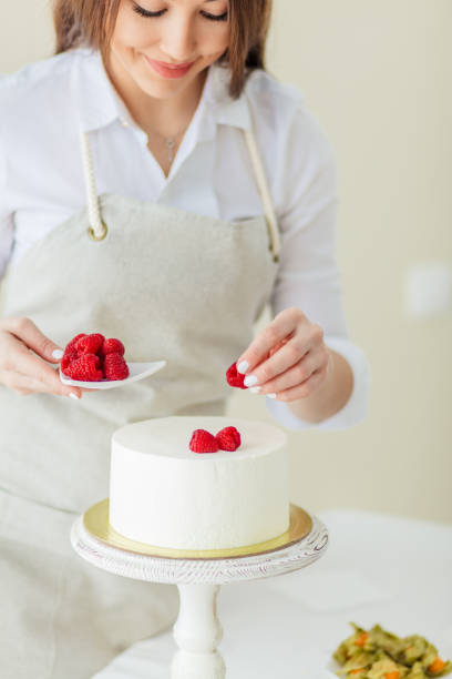 istock smiling pleasant girl decorating cake with raspberries 1227095439