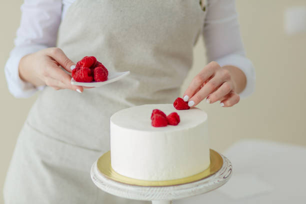 istock girl in apron placing berries on the cake 1227095487