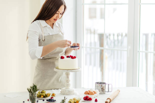 istock pleasant confectioner decorate the cake with blueberries and raspberries 1227095524