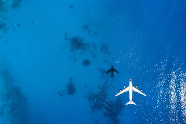 Photo of Aerial top down view of an airplane flying over blue sea