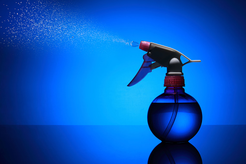 Blue glass cleaner spray spraying dispersion pulverizer atomizer on a blue background isolated