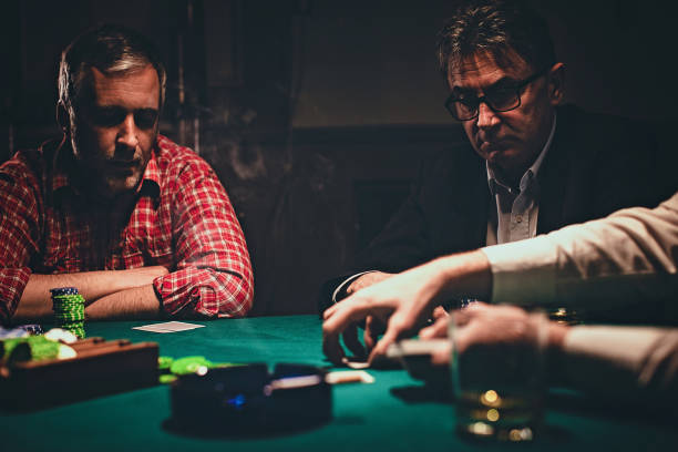istock Men playing poker game late by night 1227099627