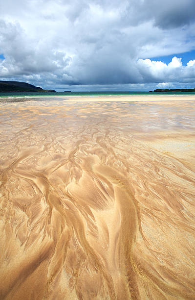 Flames of sand Stream flowing widely over the beach into the green and blue sea. Air partly clouded. Near abstract patterns. beach fire scotland stock pictures, royalty-free photos & images