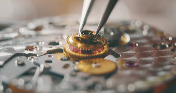 Portrait close up of a professional watchmaker repairer working on a vintage mechanism clock in a workshop. Portrait close up of a professional watchmaker repairer working on a vintage mechanism clock in a workshop. watch timepiece stock pictures, royalty-free photos & images