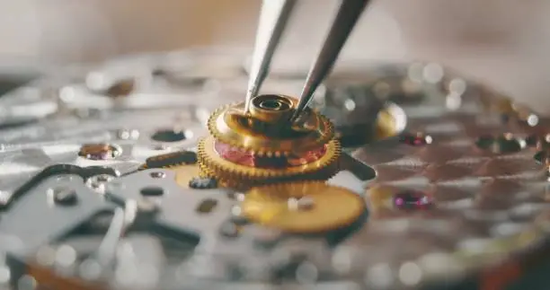 Photo of Portrait close up of a professional watchmaker repairer working on a vintage mechanism clock in a workshop.