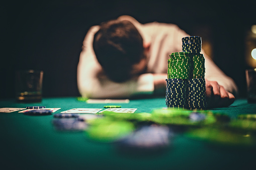 One young man playing poker game late by night and losing in game.