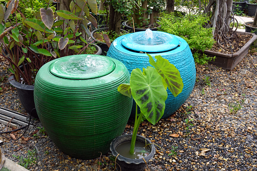 Green Jar and Blue jar of water springing. Jar with flowing water spring in the garden. water overflow