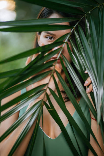 istock young lady covering face with exotic green plant 1227105809