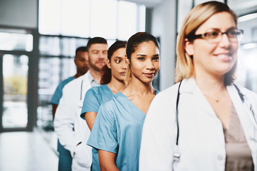 Portrait of a young nurse standing in a line amongst her colleagues in a hospital