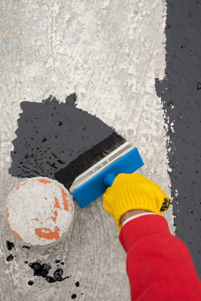 istock Worker applies bitumen mastic on the foundation 1227107174