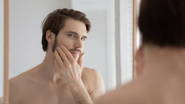 istock Young Caucasian man apply cream in home bathroom 1227112388