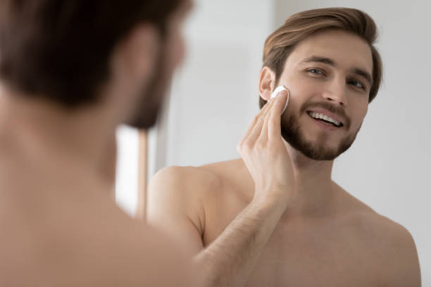 istock Smiling young man clean face with toner in bath 1227112912