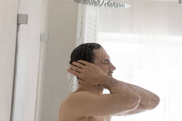 istock Young man taking shower in home bathroom 1227112957