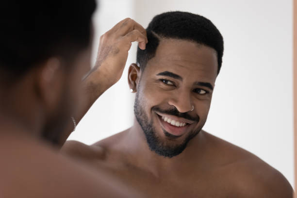 istock Smiling african American man look in mirror in bathroom 1227113107