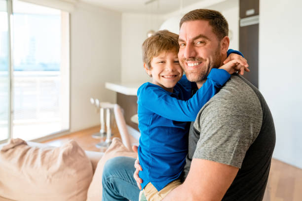 istock Little boy hugging his father at home 1227116373