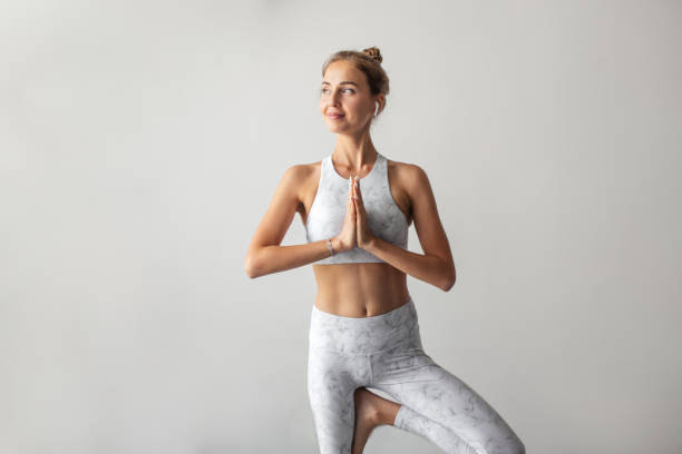 istock Woman working out indoors, standing in Tree Pose on window sell 1227118596