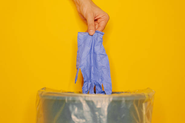 istock Hand putting used dirty surgical glove to a garbage bin 1227120525