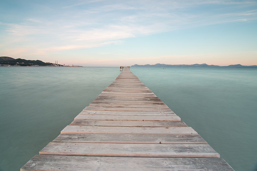 Image of a wooden pier to the sea, with silky water on the island of Mallorca. Long exposure technique