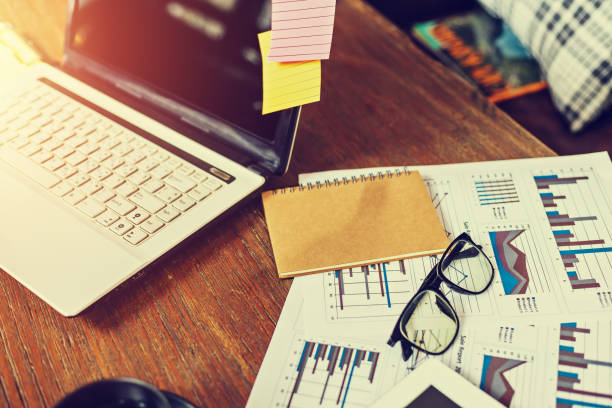 istock Glasses, book, paper graph and laptop on the table. 1227126184