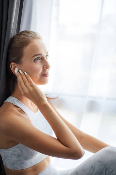 istock Woman in earbuds looking at camera and smiling over white wall 1227131469