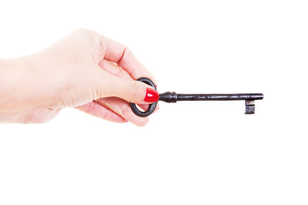 istock Female hand holds an old key. Isolated on a white background. 1227133984