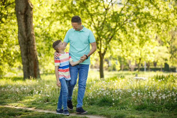 istock Father and son holding hands and walking through park 1227134011