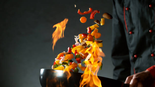 istock Closeup of chef throwing vegetable mix from wok 1227134136