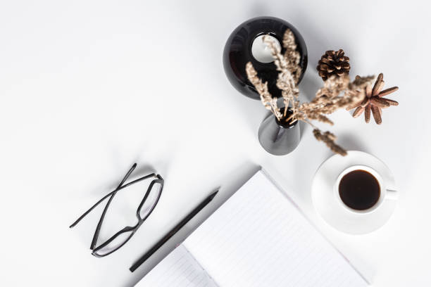 istock Directly above view - White desk, pen, note pad, pine cone, eyeglasses and coffee 1227134180