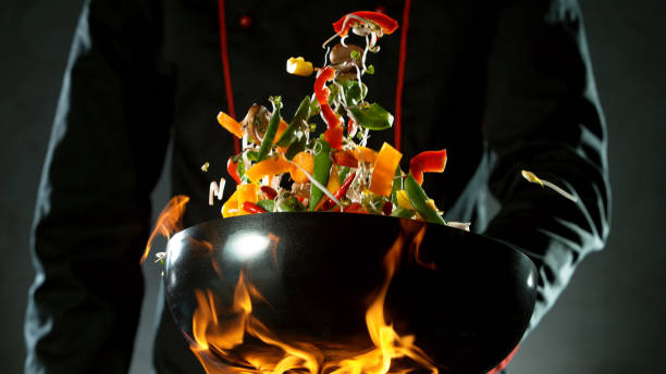 istock Closeup of chef throwing vegetable mix from wok 1227134239