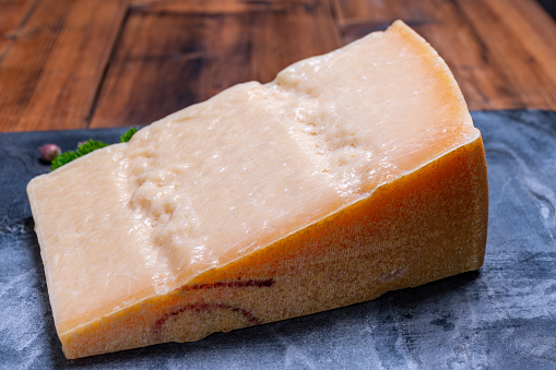 Big wedge of parmigiano-reggiano parmesan hard Italian cheese made from cow milk or Grana Padano  close up