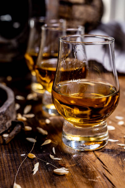 kleine proefglazen met oude schotse whisky op oude donkere houten uitstekende lijst met gerstkorrels - spey scotland stockfoto's en -beelden