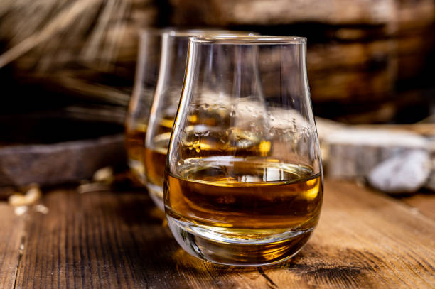 speyside scotch whisky proeverij op oude donkere houten vintage tafel met gerstkorrels - spey scotland stockfoto's en -beelden