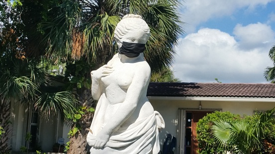 In Golden Beach, United States a classical female lawn sculpture has a face mask on in the front yard of a home during the Coronavirus pandemic.